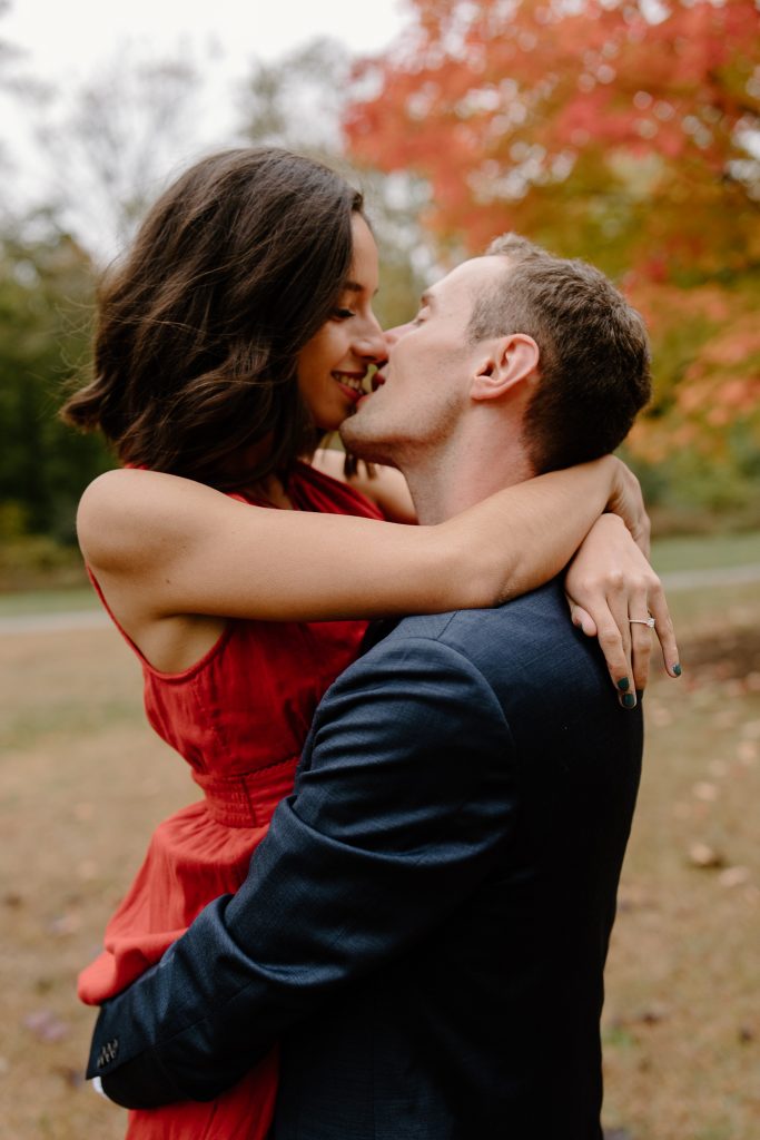close up portrait of man and woman in red dress kissing