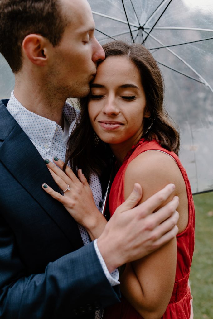 man kissing woman in rain