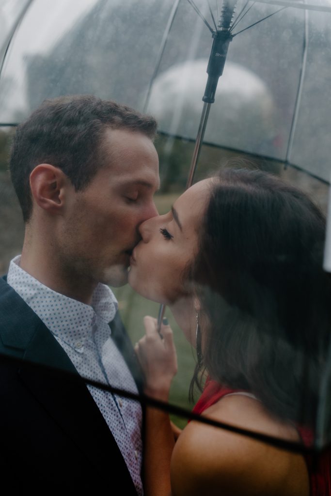 man and woman kissing under umbrella