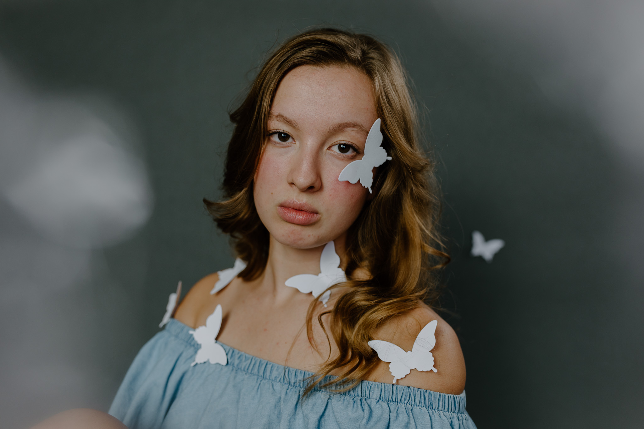 girl looking directly at camera covered in white butterflies