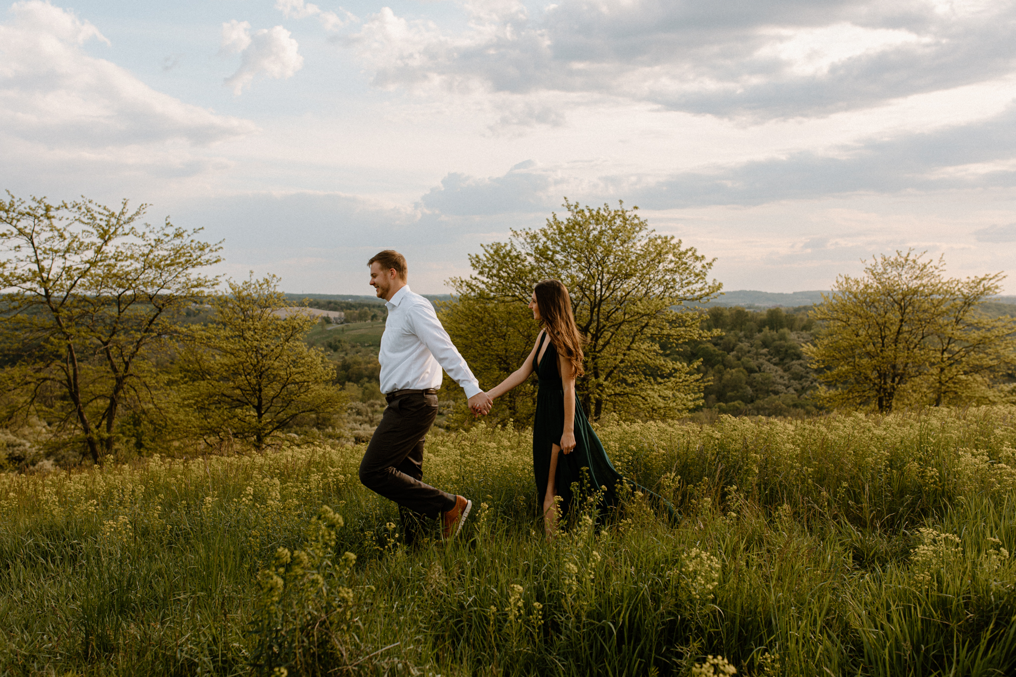 couple walking through a field during sunset