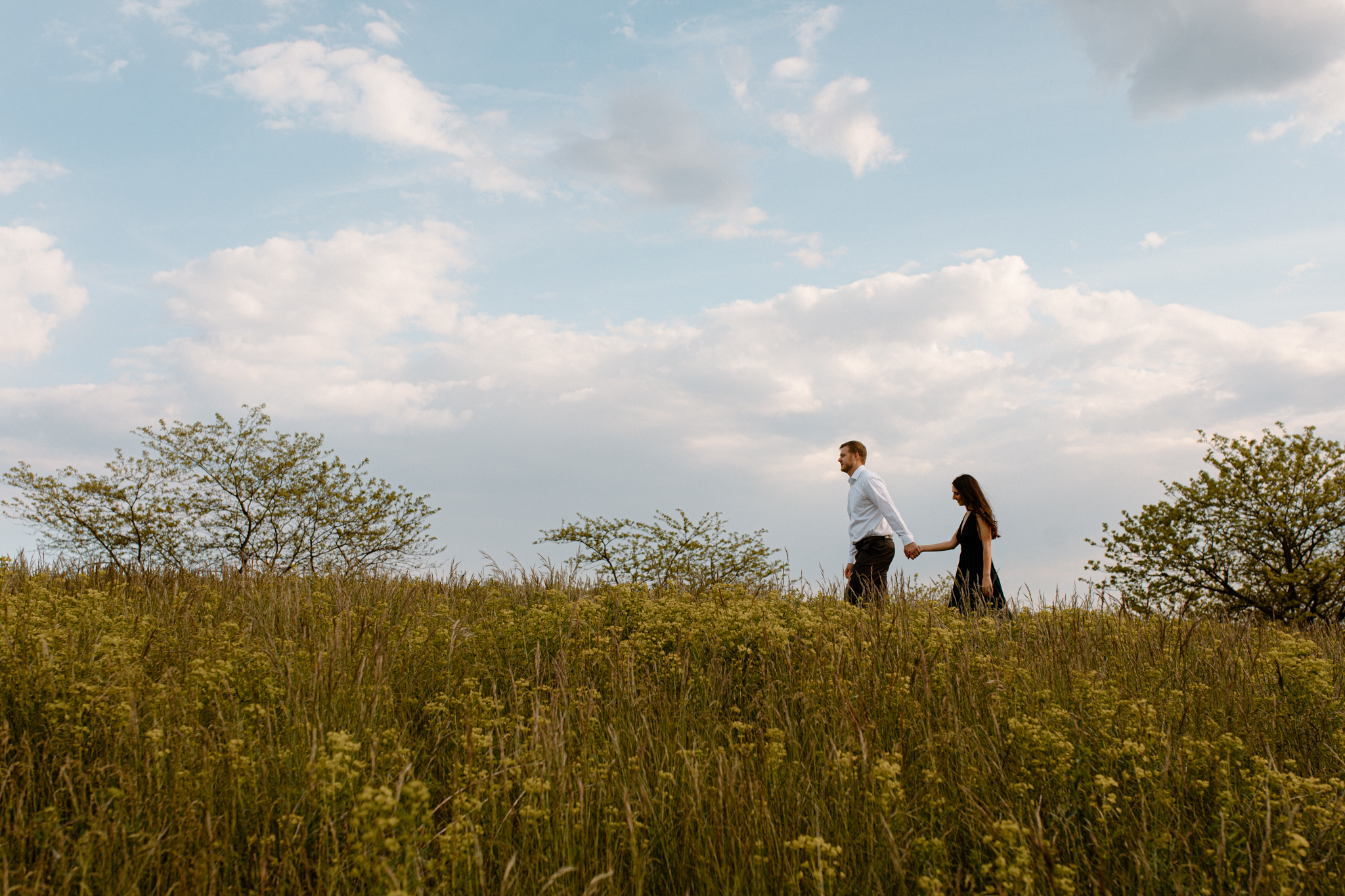 people holding hands, walking through a field