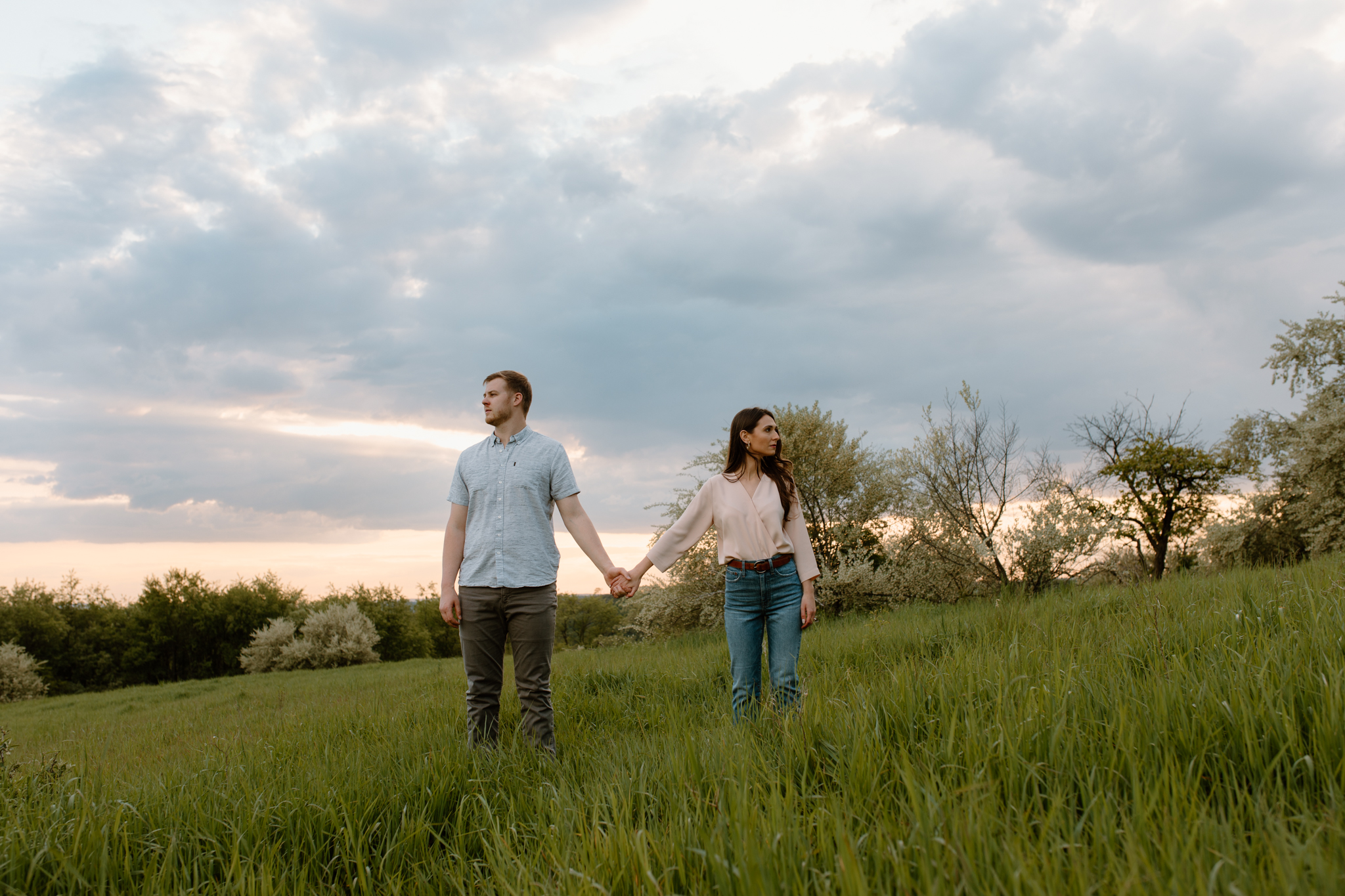 couple standing in field looking different directions