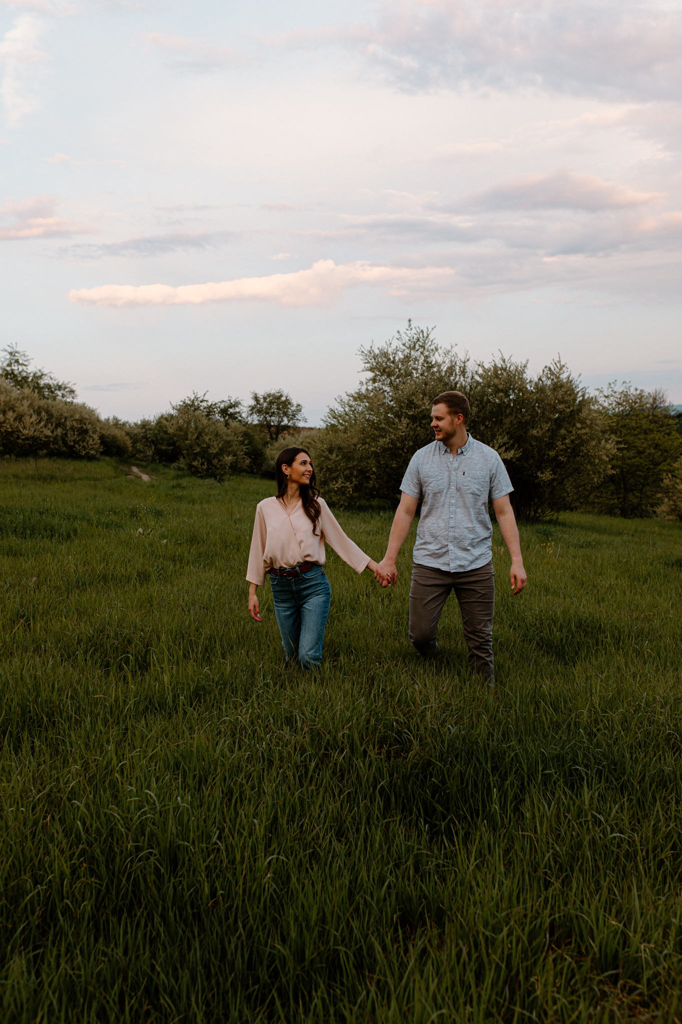 couple holding hands and walking in field